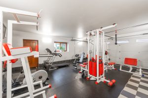 Modern interior design of new spacious fitness gym for home sport training and heavy weightlifting in garage of big house